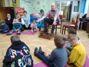 Pan Piotr opowiada dzieciom i pracownikom przedszkola o przyniesionym instrumencie