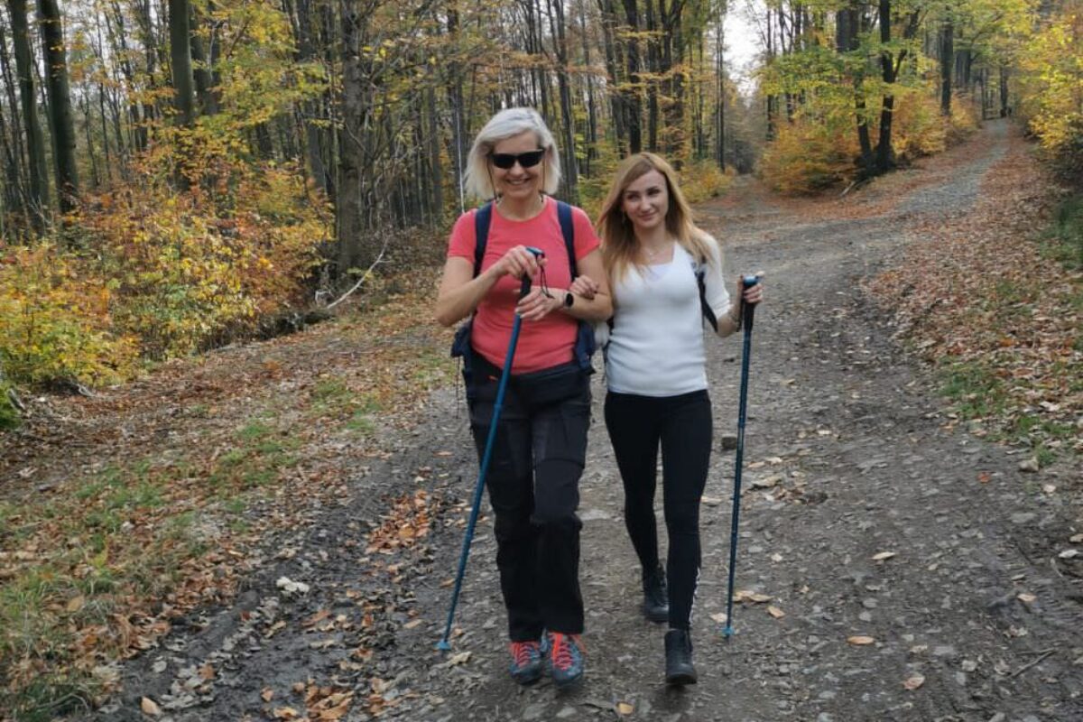 Osoba niewidoma z asystentem osobistym na spacerze w lesie.