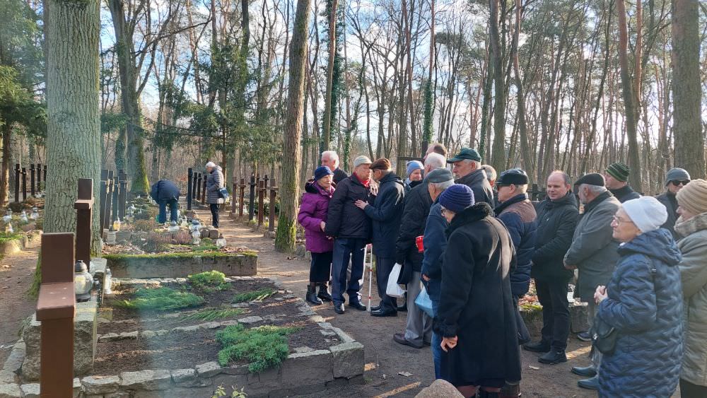 Grupa osób przy grobie Henryka Ruszczyca na cmentarzu w Laskach