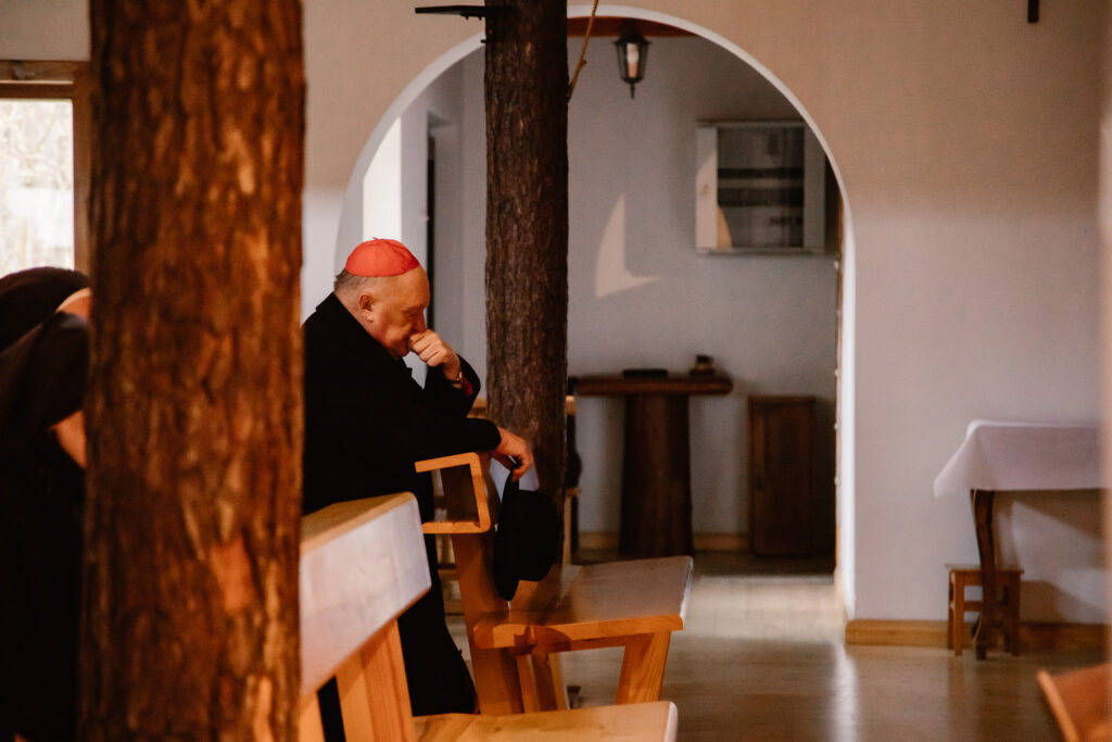 Kardynał Kazimierz Nycz klęczy w ławce w kaplicy.