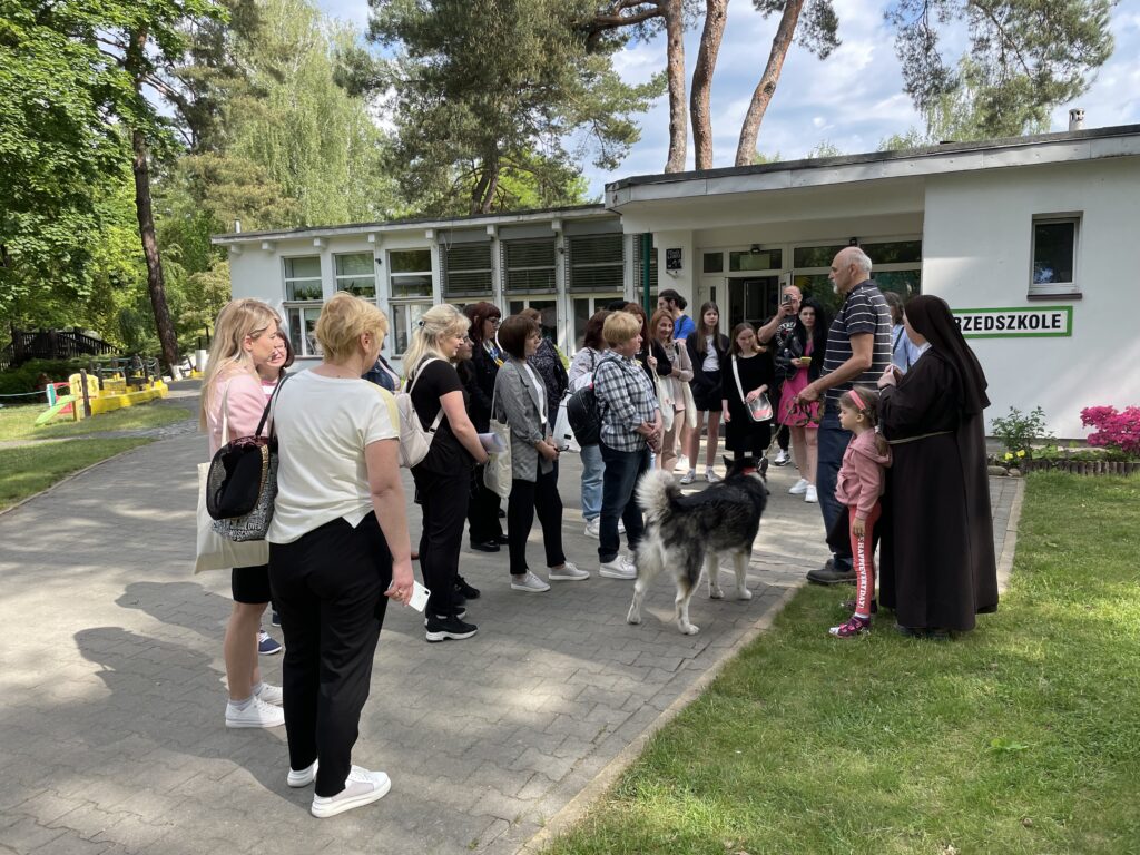 Uczestnicy wizyty studyjnej rozmawiają o hipoterapii i dogoterapii przed przedszkolem.