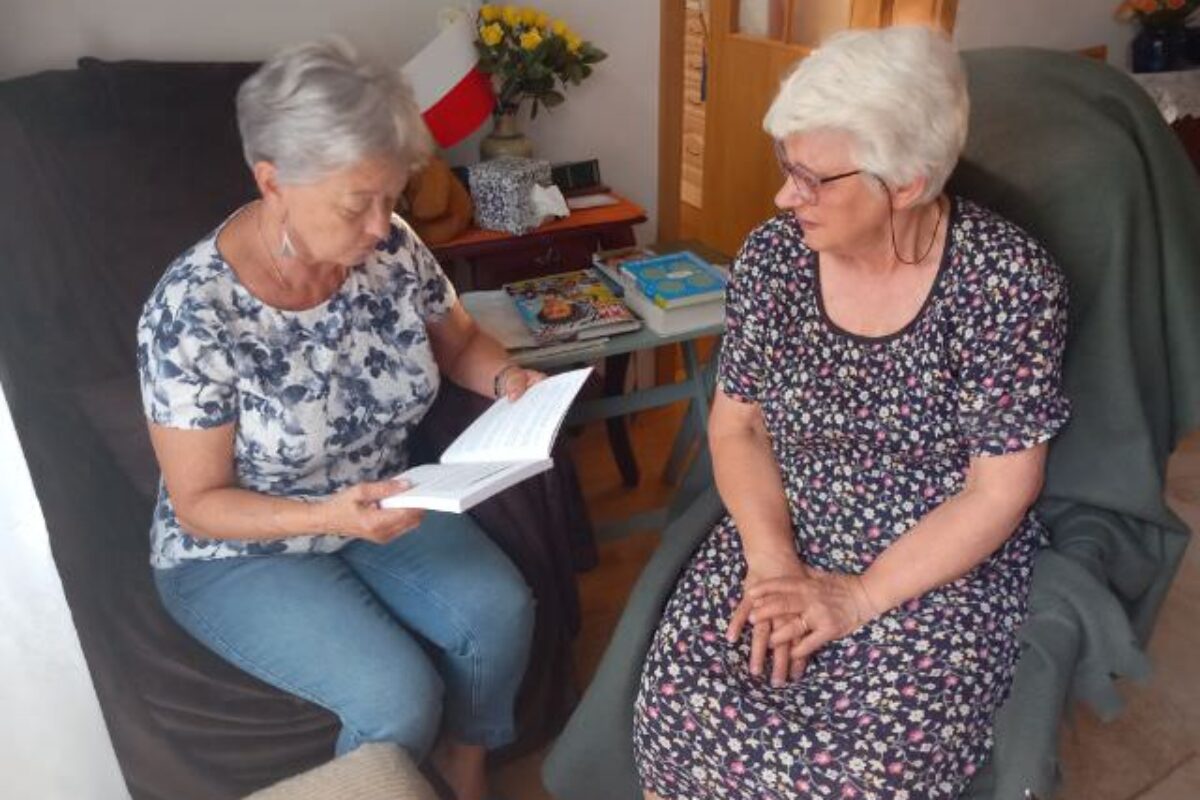 Asystentka czyta książkę osobie niepełnosprawnej.