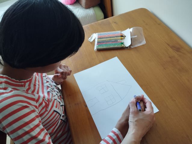 Asystent pomaga osobie niepełnosprawnej rysować.