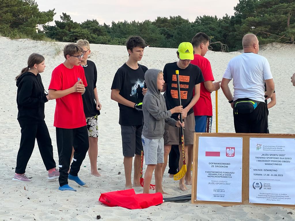 Uczniowie na plaży z kijami do hokeja.