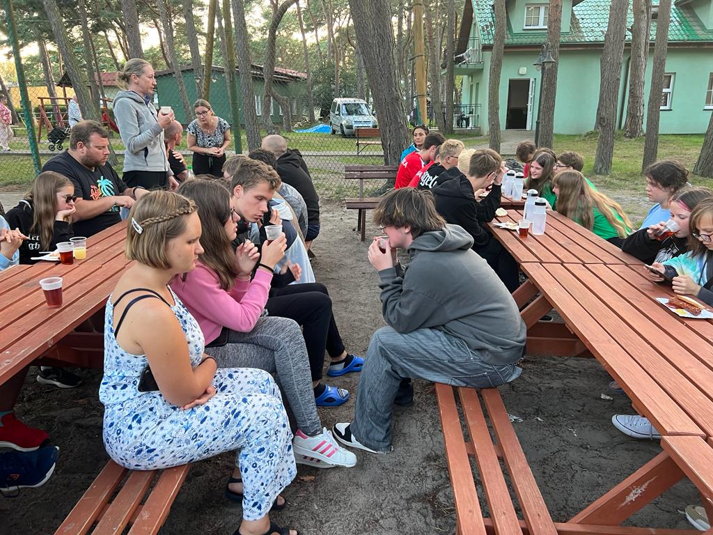 Posiłek przy stołach na dworze.
