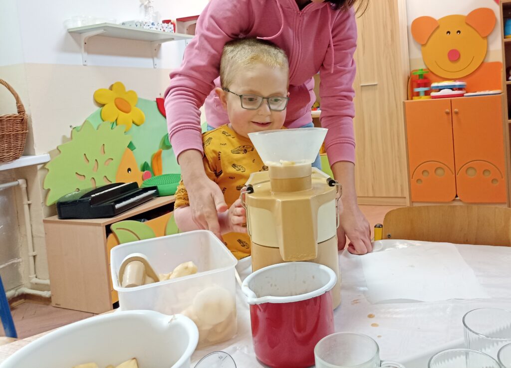 Uśmiechnięty chłopiec ogląda sokowirówkę.
