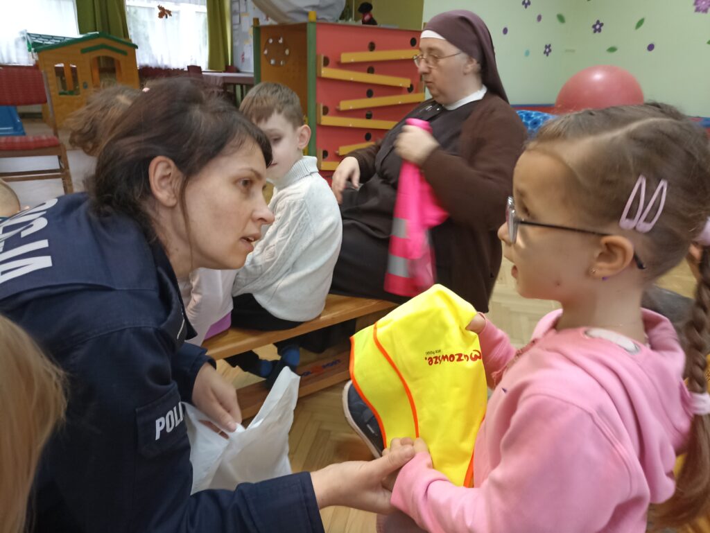 Pani policjantka wręcza kamizelkę odblaskową Weronice.
