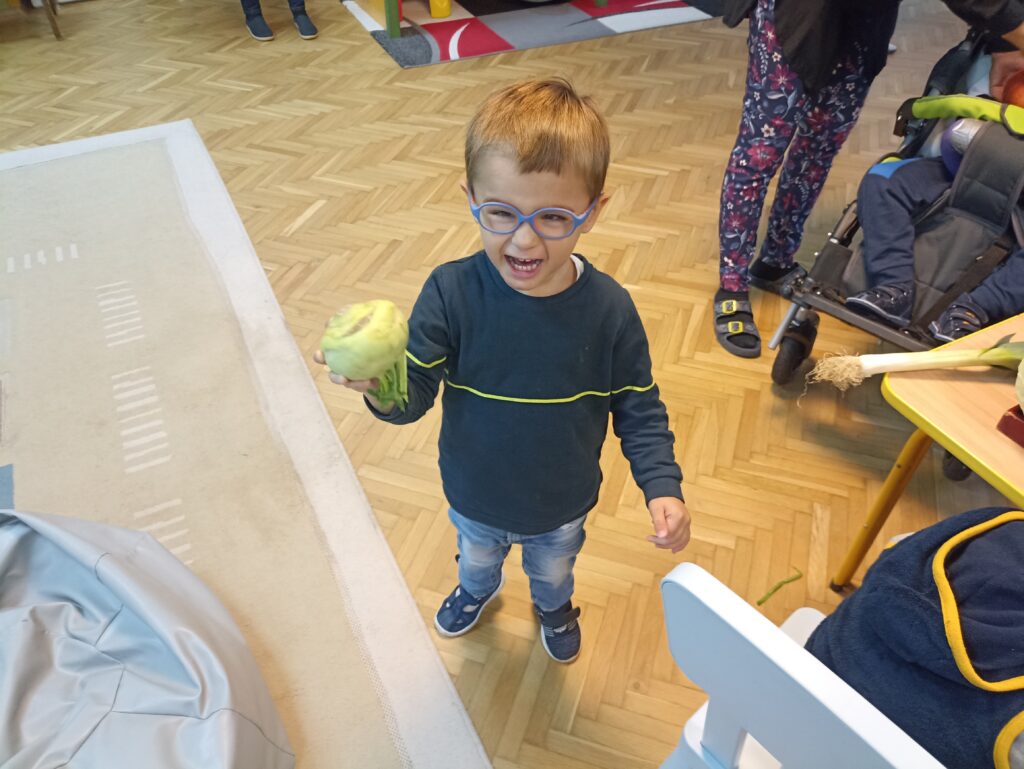 Uśmiechnięty chłopiec trzyma kalarepę.
