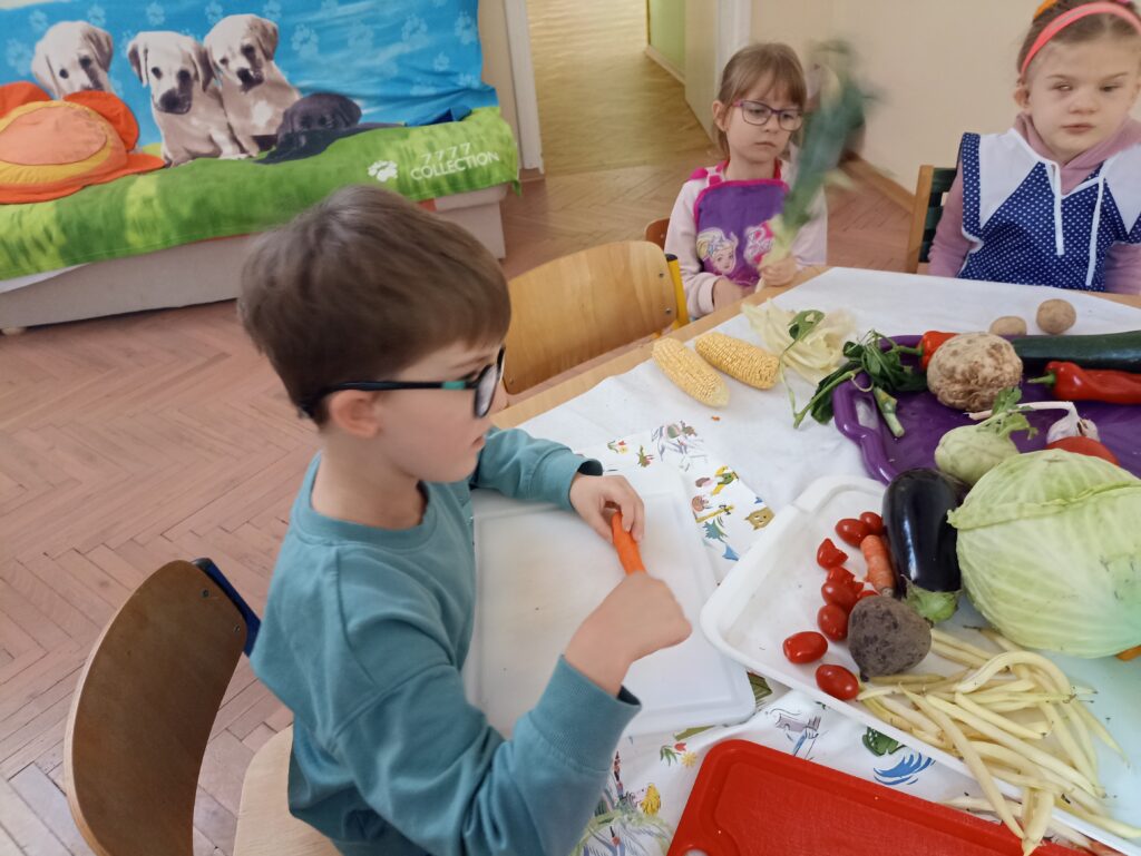 Dzieci kroją warzywa.