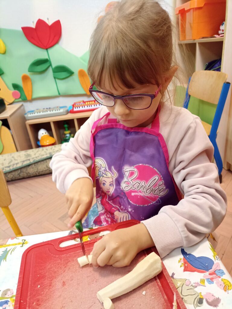 Dziewczynka kroi obraną pietruszkę.