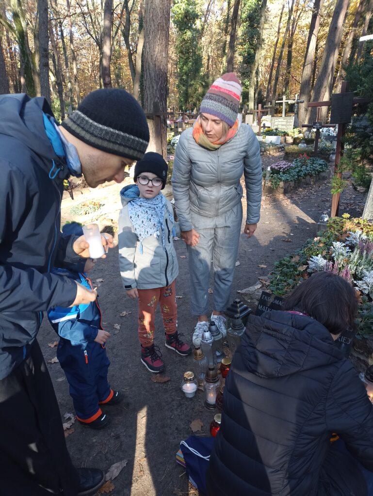 Pani i Ksiądz z przedszkolakami przy grobie.