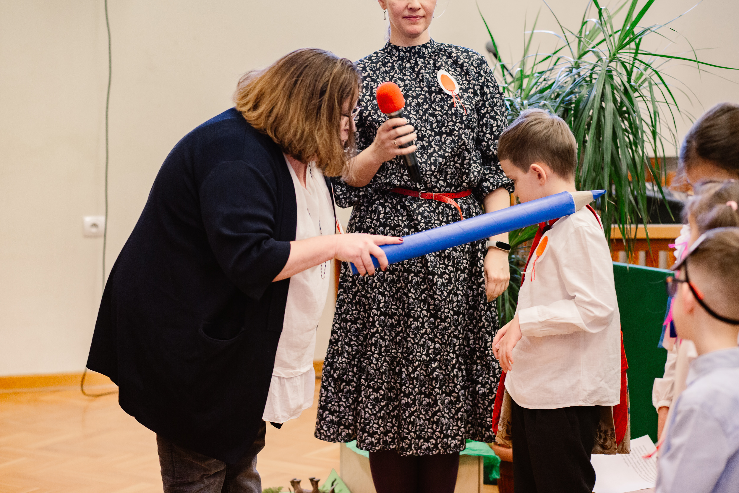 Dyrektor Dorota Gronowska pasuje dużym ołówkiem ucznia.