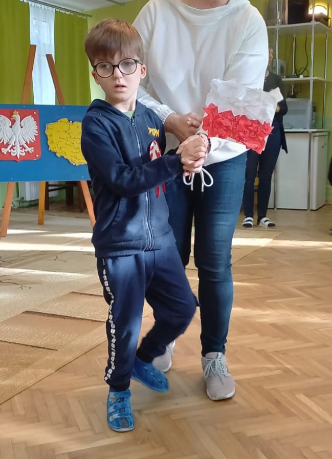 Chłopiec z flagą biało - czerwoną w ręku.