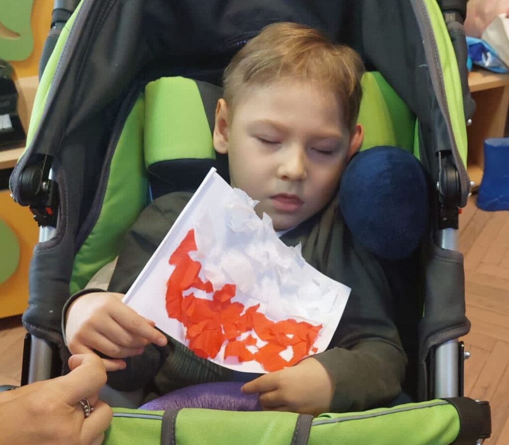 Chłopiec z papierową flagą biało - czerwoną.