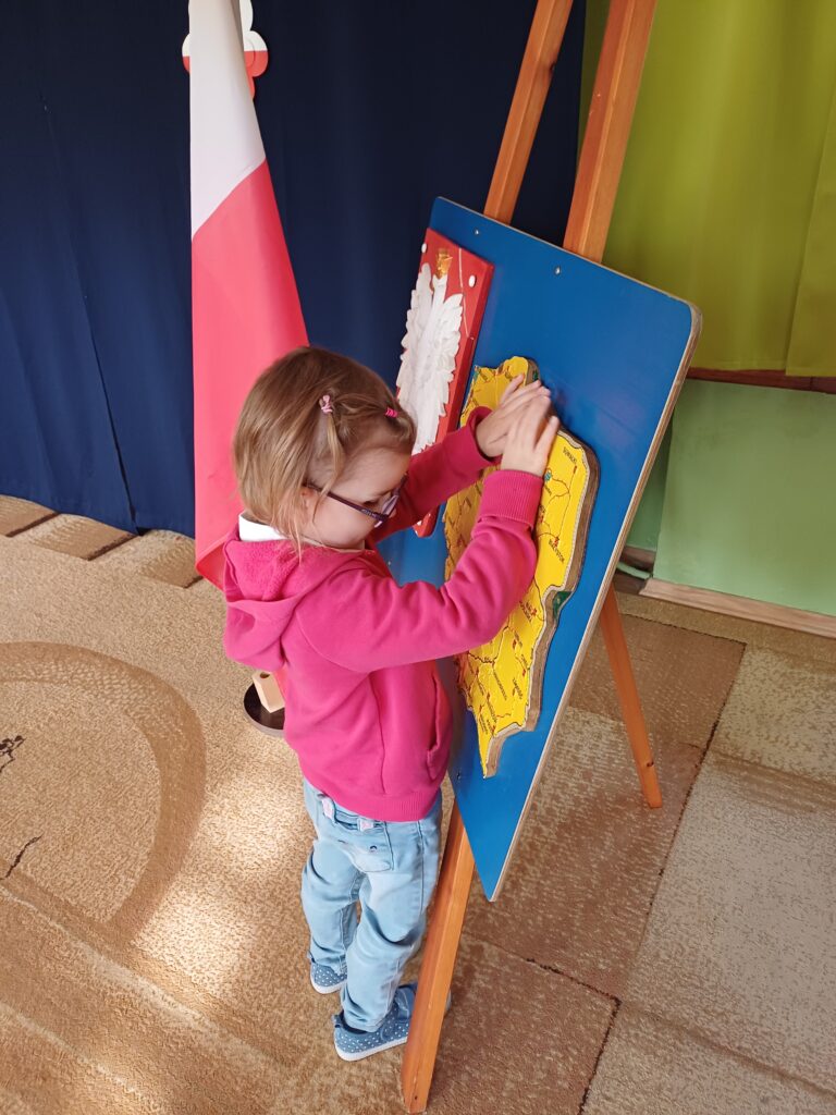 Dziewczynka ogląda dłońmi wypukłą mapę Polski.