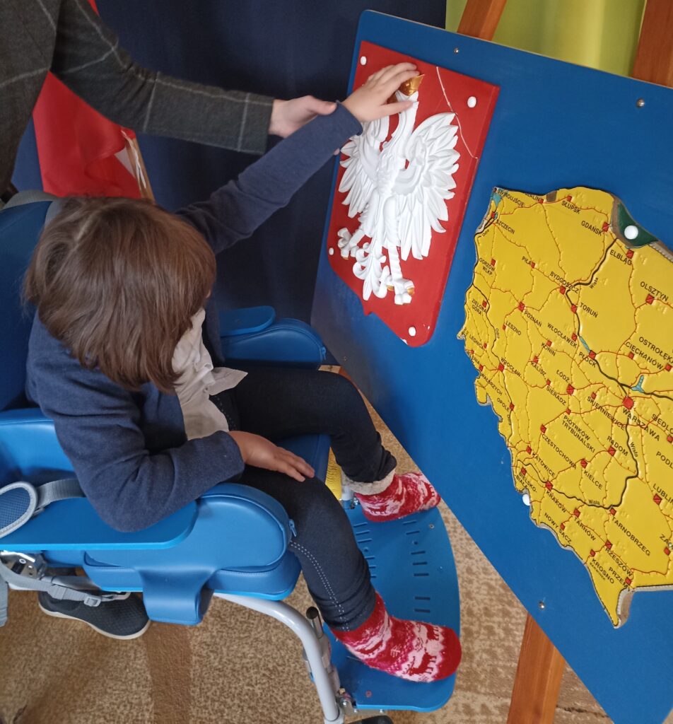 Dziewczynka ogląda dłońmi wypukłe Godło Polski.