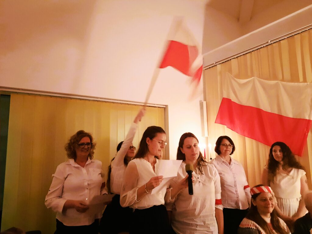 Dziewczęta z grupy VI z wychowawczyniami w strojach biało- czarnych z opaskami patriotycznymi na lewym ramieniu podczas śpiewania pieśni Przybyli Ułani