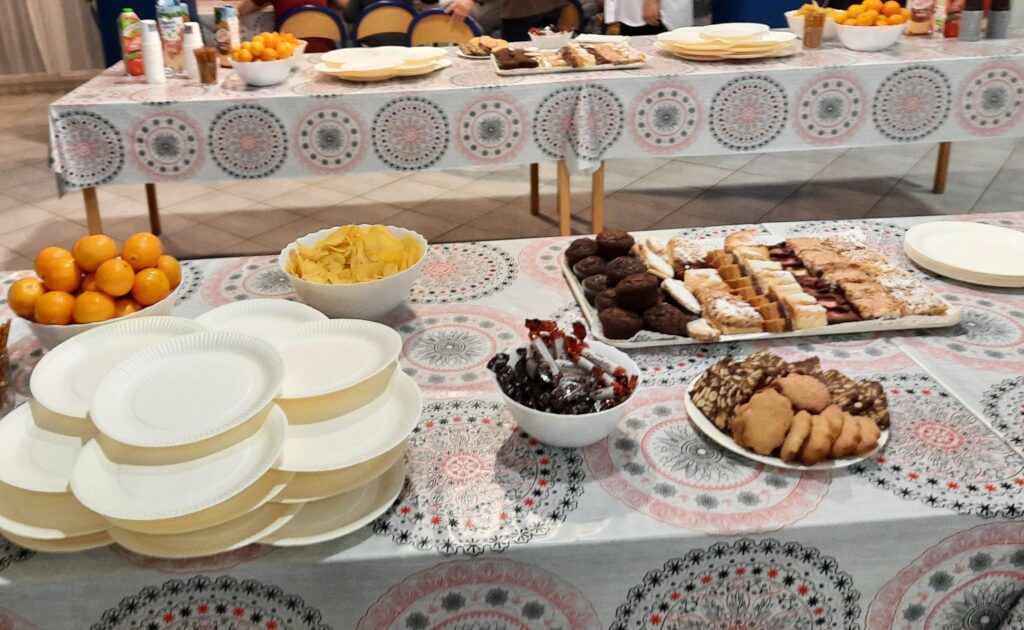 Na jadalni przygotowane stoły na których stoją ciasta, ciasteczka , słone przekąski, chipsy, mandarynki