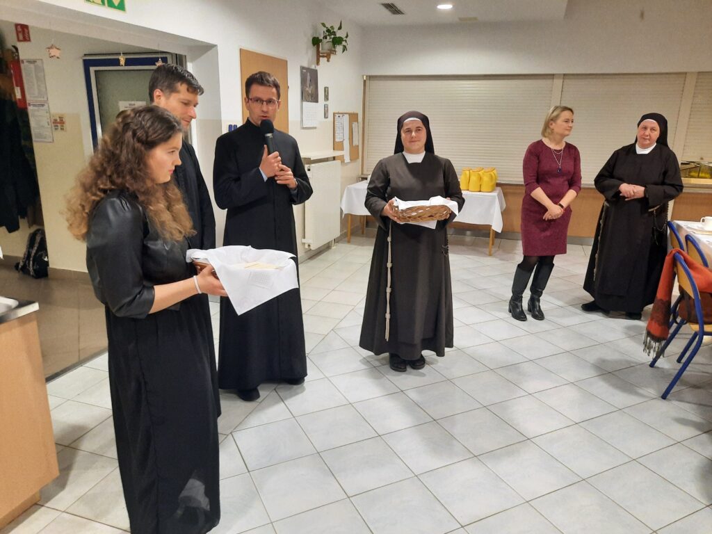 Na jadalni księża Marek i Sebastian oraz  Siostra Marta i Ewa trzymają koszyki z opłatkami