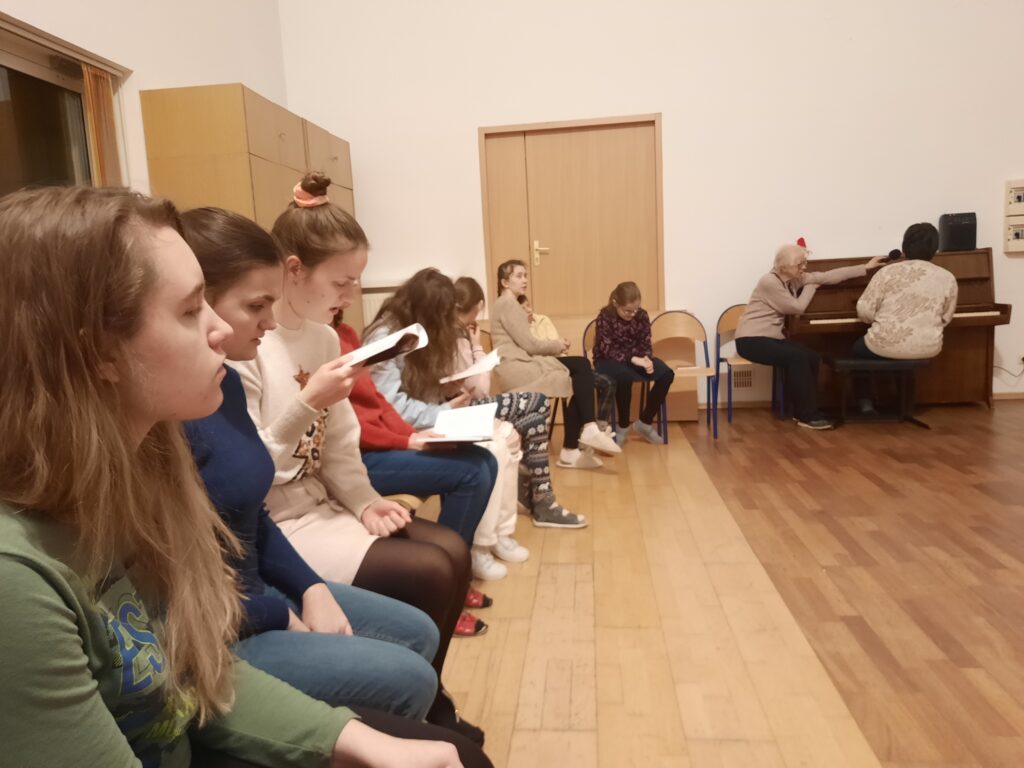 Ewa gra na pianinie a dziewczęta śpiewają kolędy