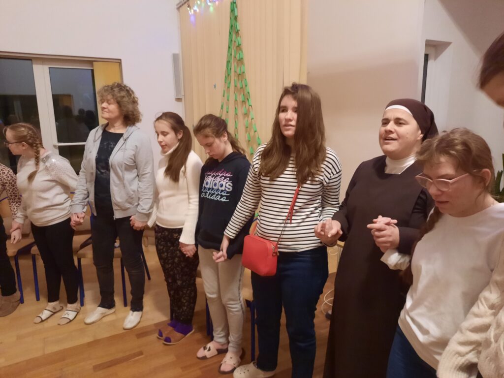 Siostra Marta z dziewczętami tworzy koło i przekazują sobie iskierkę przyjaźni