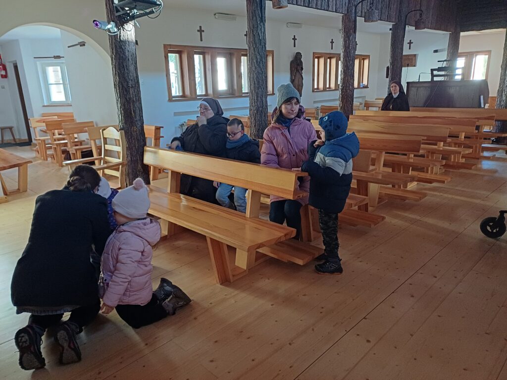 Dwie dziewczynki klęczą z Panią wychowawczynią, chłopiec z siostrą siedzi w ławce. Chłopiec stoi przy Pani wychowawczyni.