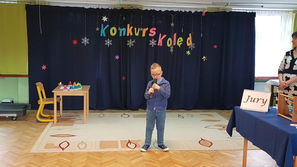 Chłopiec z mikrofonem śpiewa kolędę.