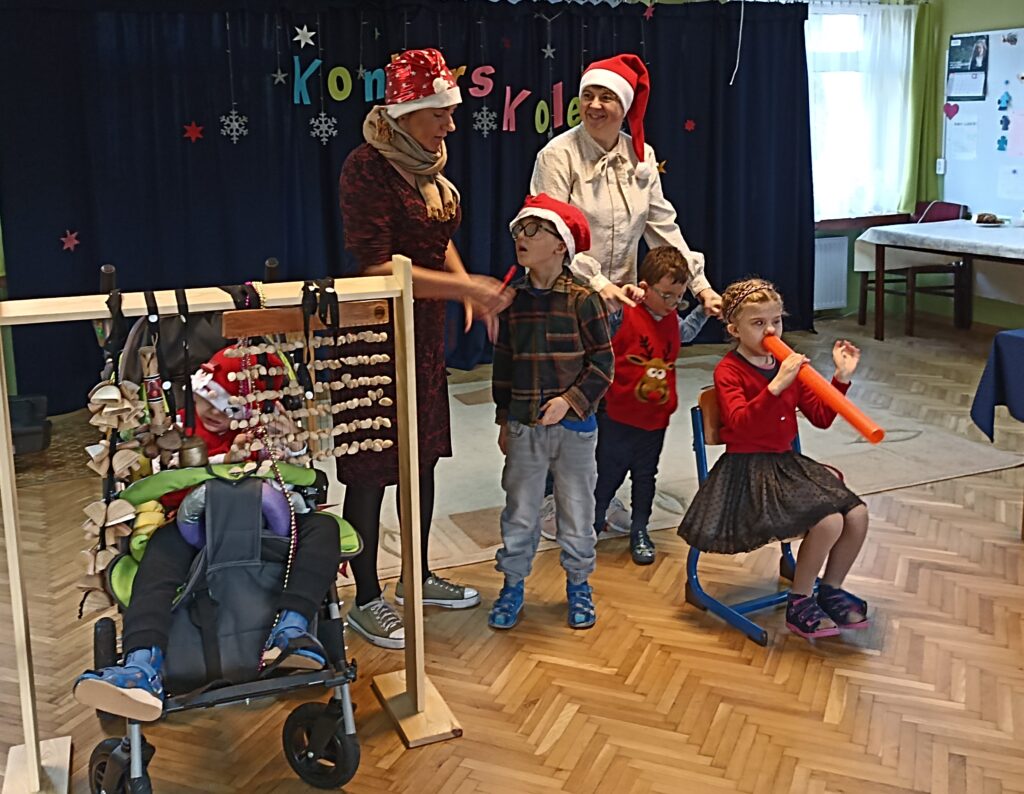 Grupa Krasnali śpiewa kolędę i gra na instrumentach.