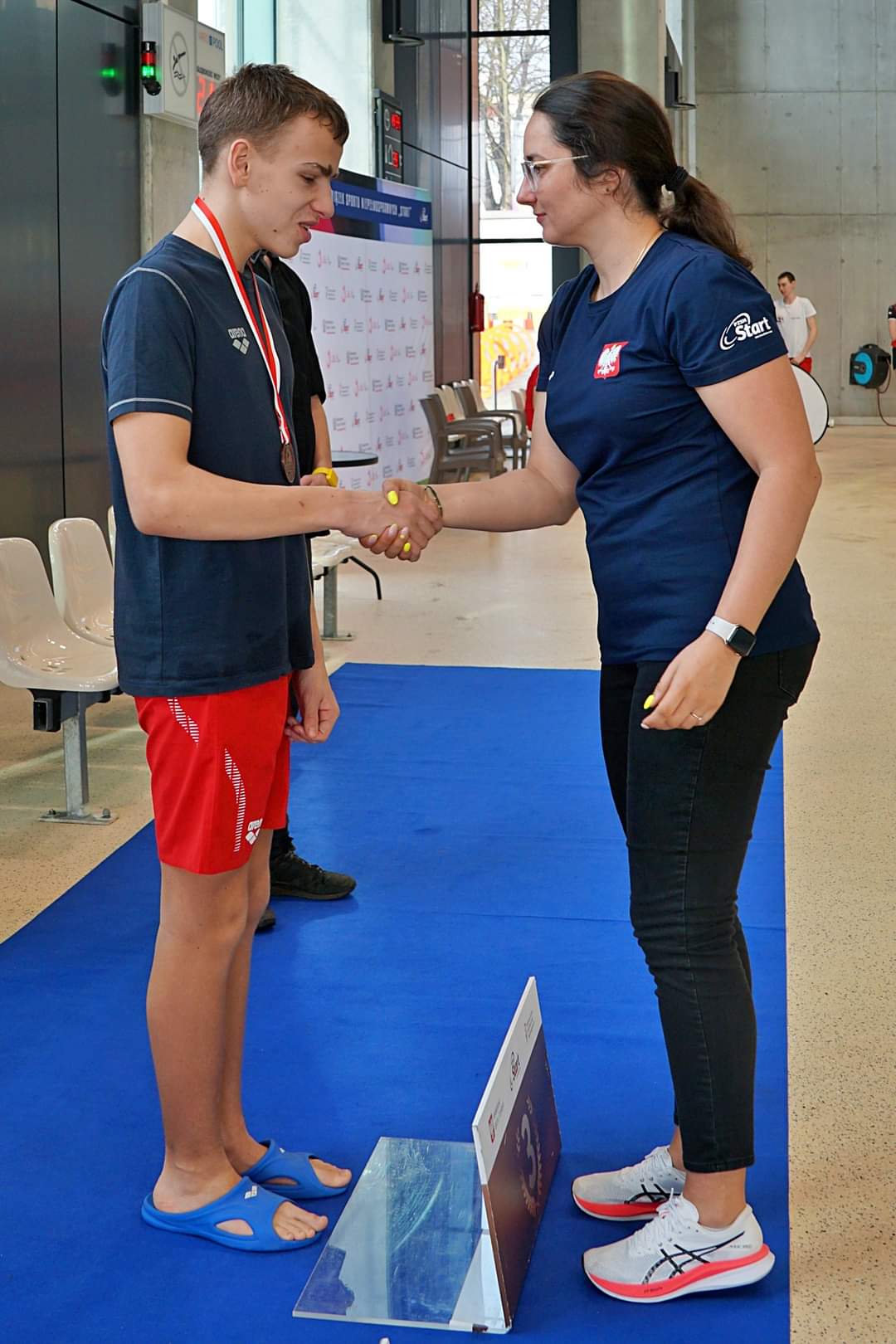 Alex odbiera medal na podium.