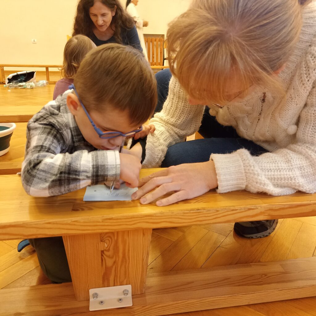 Chłopiec z Panią pochyleni nad kartką papieru.
