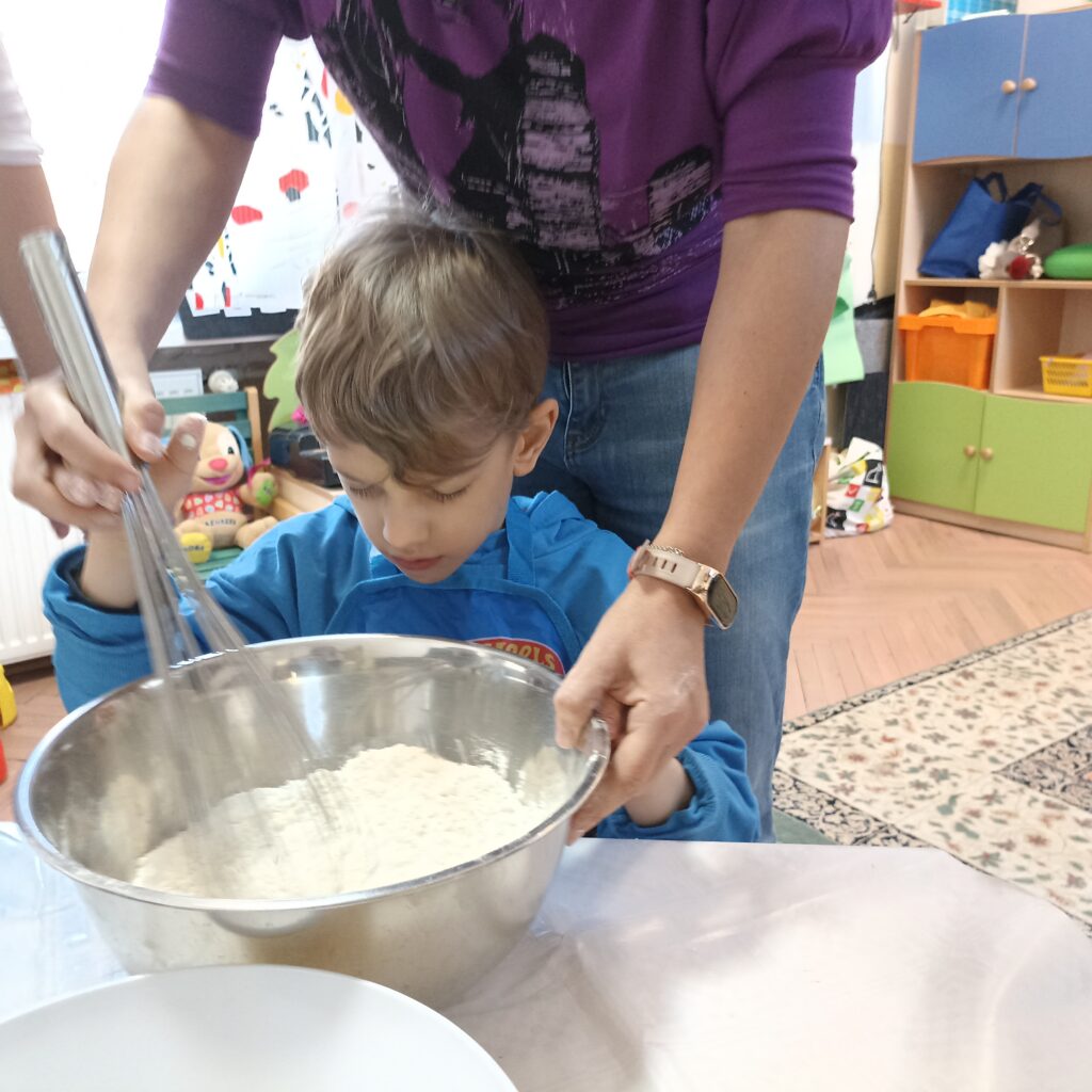 Chłopiec z panią wspólnie mieszają składniki w misce.