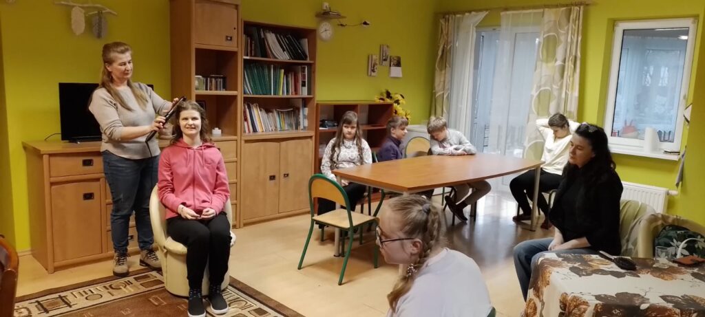 Pani fryzjerka tworzy  loki na głowie Pauliny