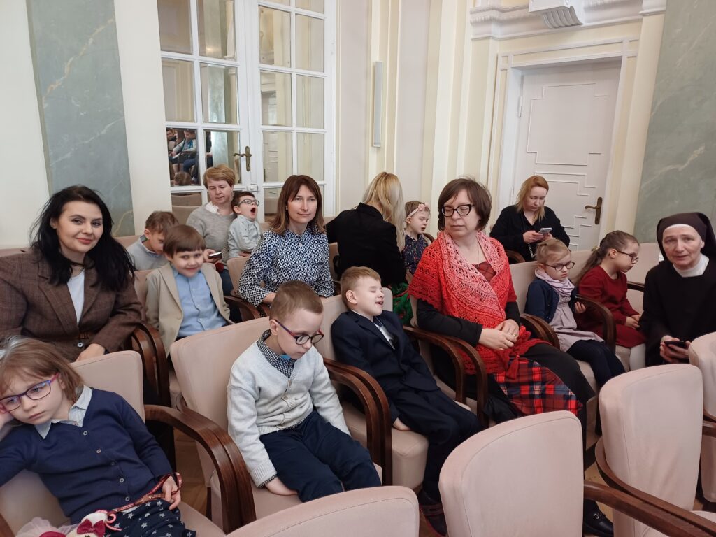 Przedszkolaki z paniami siedzą na krzesłach w Filharminii.