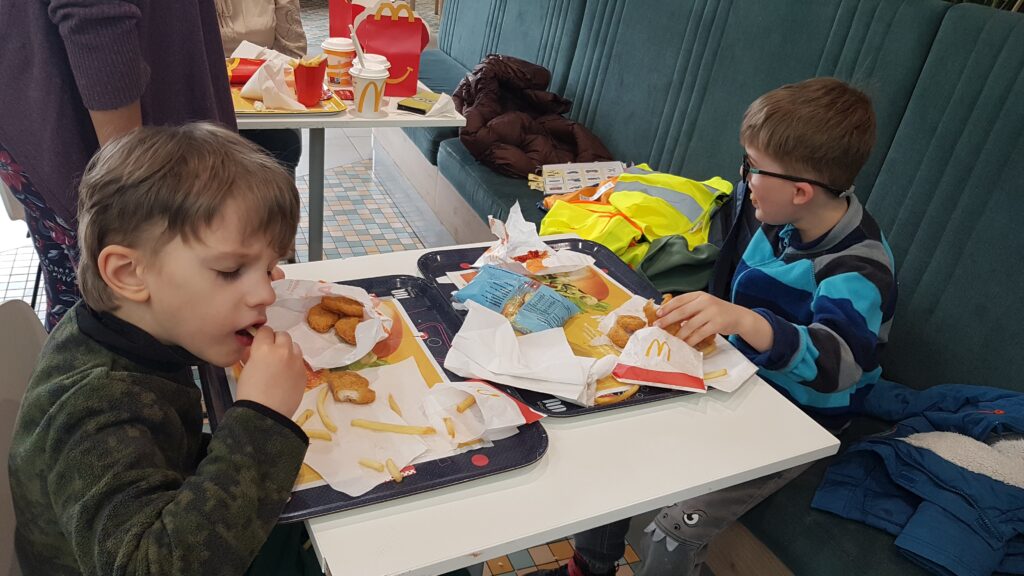 Przedszkolaki siedzą przy stole, na którym jest jedzenie z Mc. Donalds'a