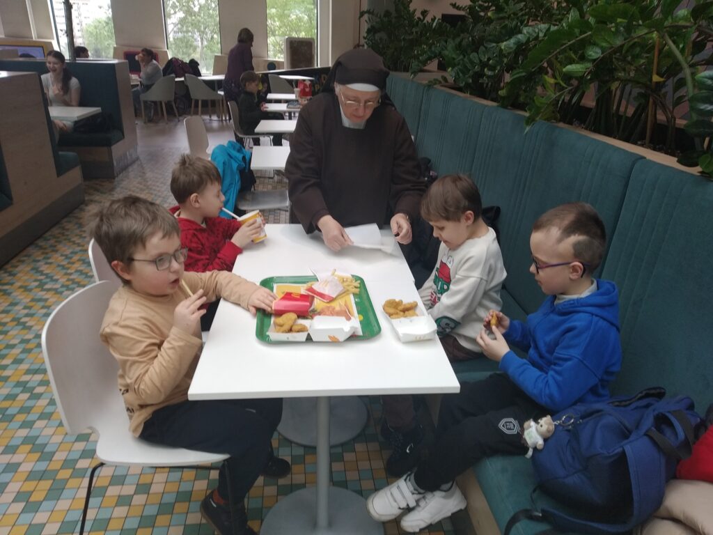 Przedszkolaki siedzą przy stole, na którym jest jedzenie z Mc. Donalds'a