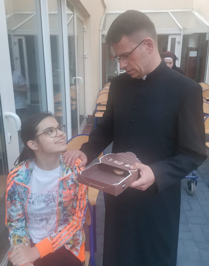 Ksiądz Marek częstuje Julię słodyczami
