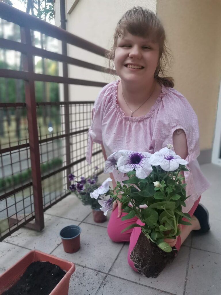 Polina  wyjmuje sadzonkę petunii z doniczki