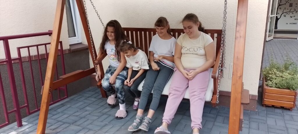 Cztery dziewczęta siedzą na huśtawce przed Internatem