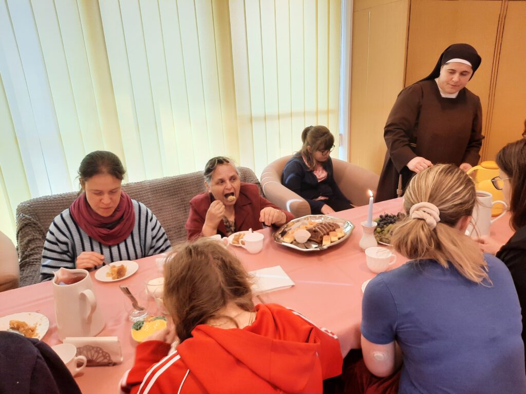 Nauczyciele, dziewczęta wraz z Siostrą Martą przy stole podczas poczęstunku