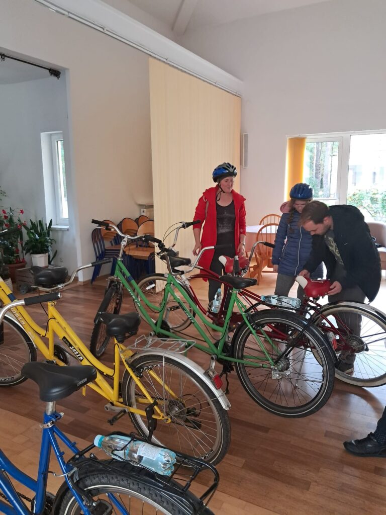 Wolontariusz Rafał wraz z panią Albertyną i Julką wykonuje przegląd roweru przed wyprawą