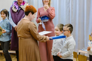 Pani dyrektor dotyka ołówkiem ramienia jednego z uczniów.