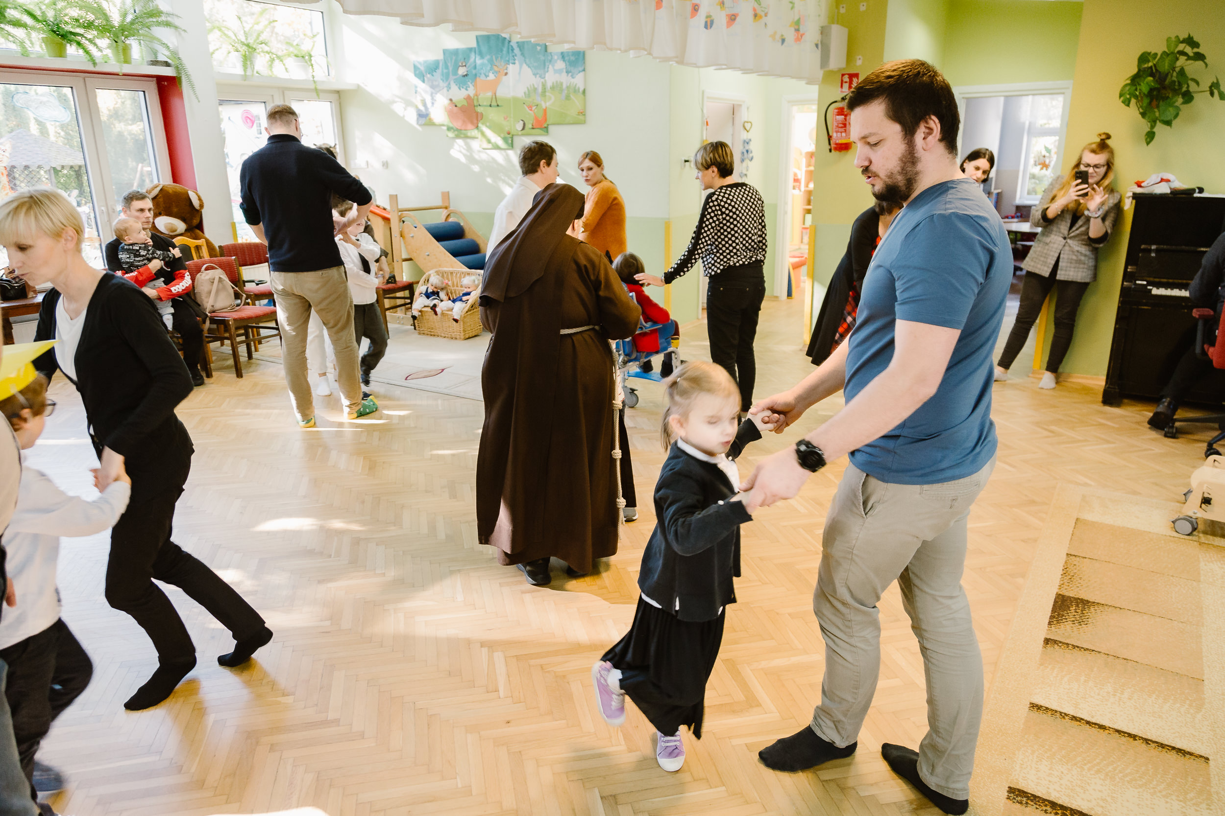 Dzieci tańczą ze swoimi rodzicami i wychowawcami.