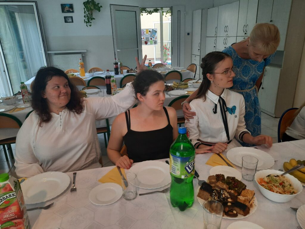 Przy stole w jadalni  siedzą dziewczęta z panią Basią