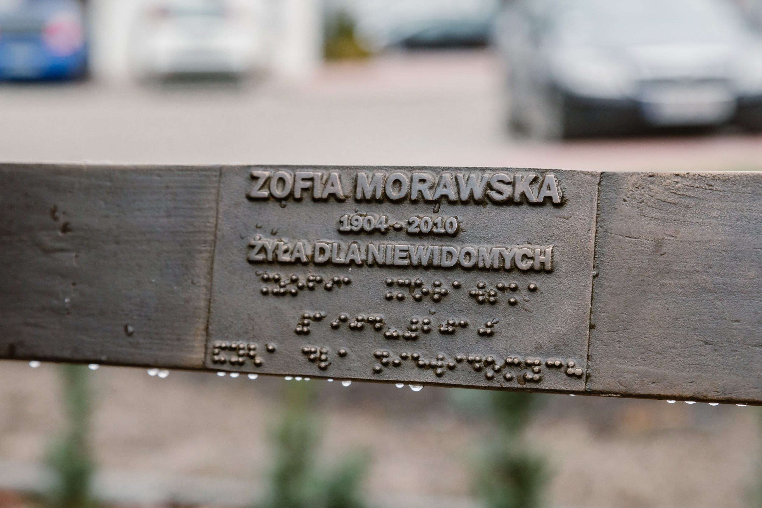 Napis na ławeczce: Zofia Morawska, 1904-2010, żyła dla niewidomych. Pod spodem zapis brajlem.