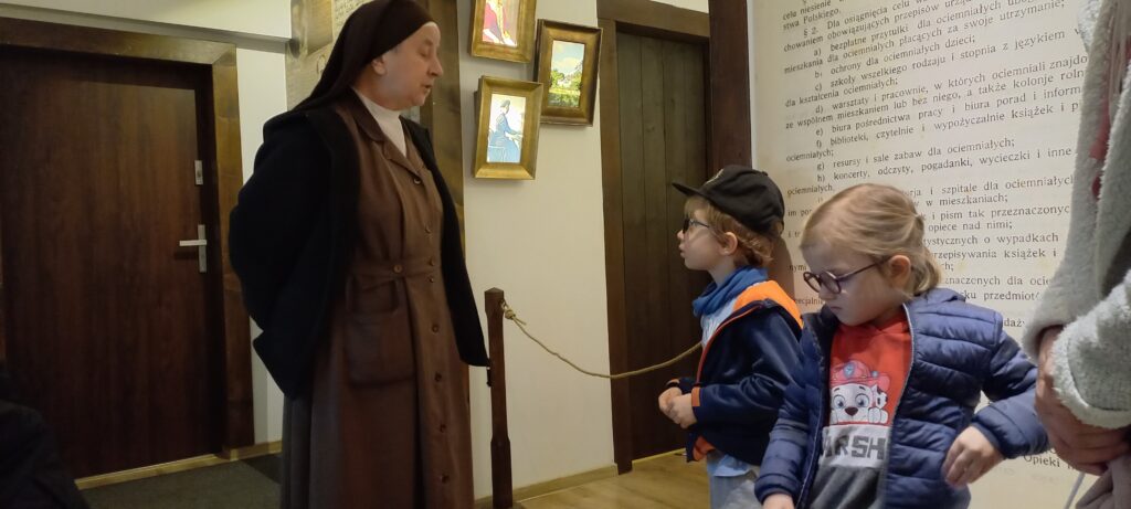 Chłopiec i dziewczynka słuchają opowiadania Siostry w Muzeum.