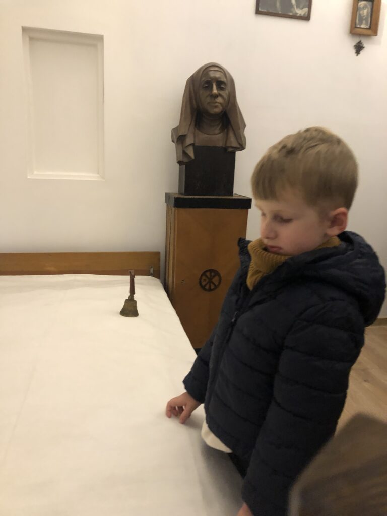 Chłopiec ogląda łóżko Matki Elżbiety Róży Czackiej.