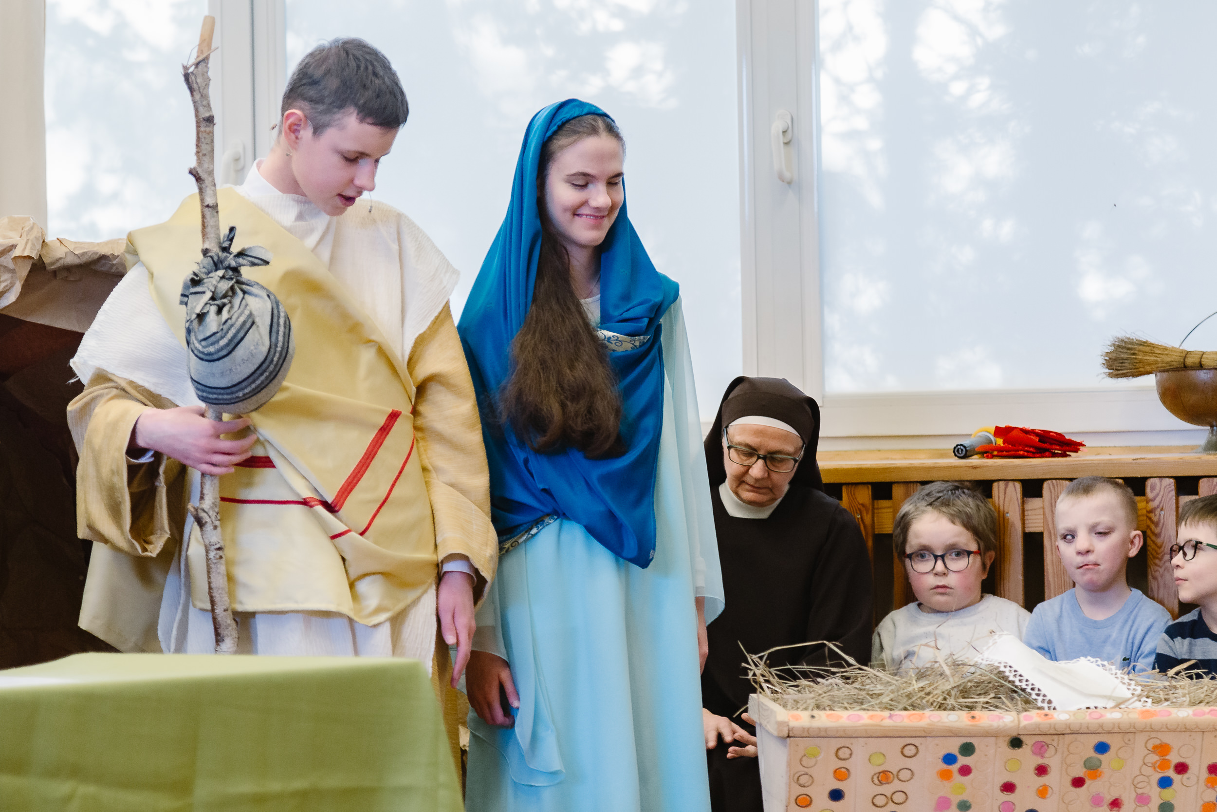 Uczniowie w stroju Maryi i Józefa, obok nich żłóbek wypełniony siankiem.