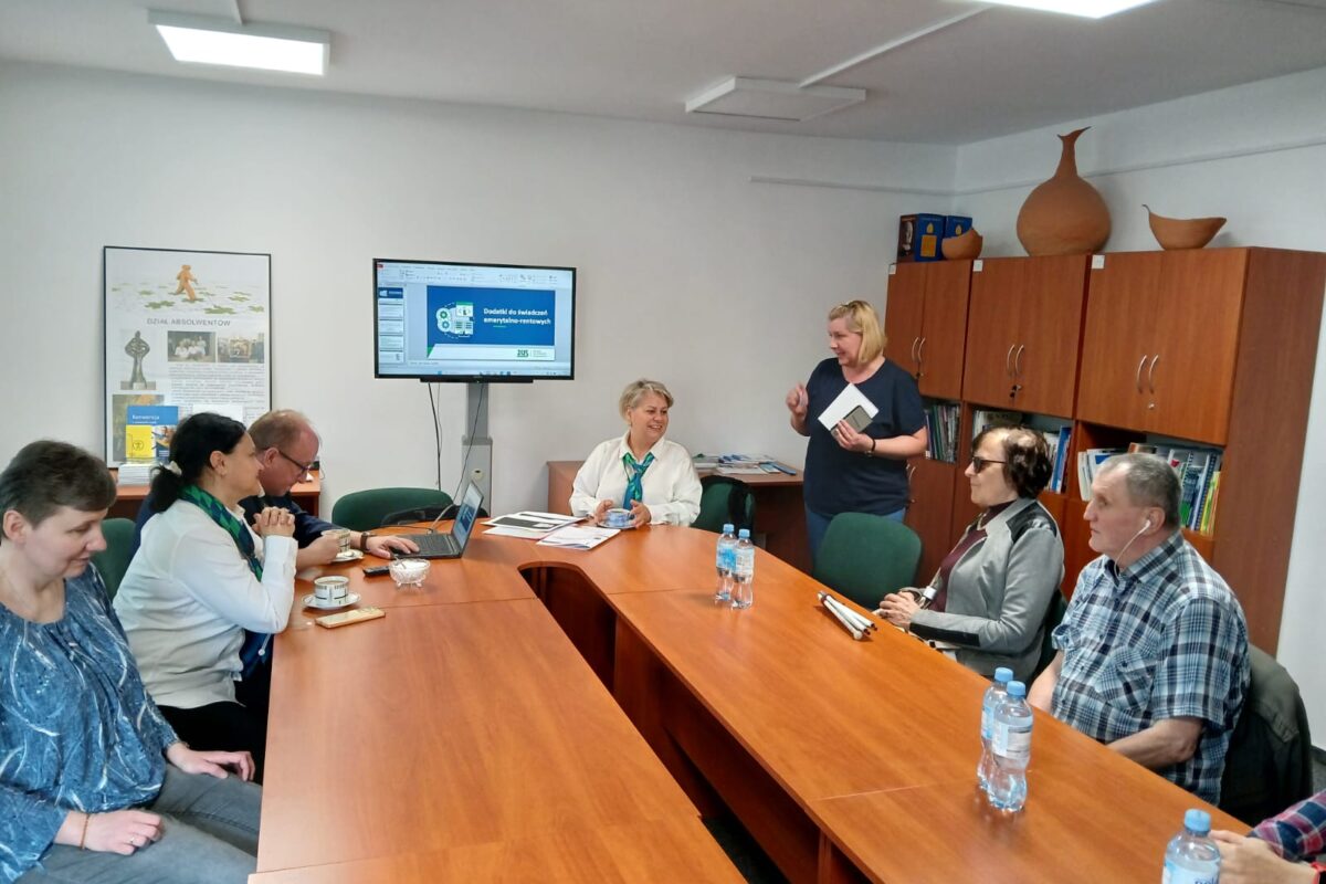 Pracownicy ZUS i uczestnicy spotkania siedzący wspólnie przy owalnym stole.