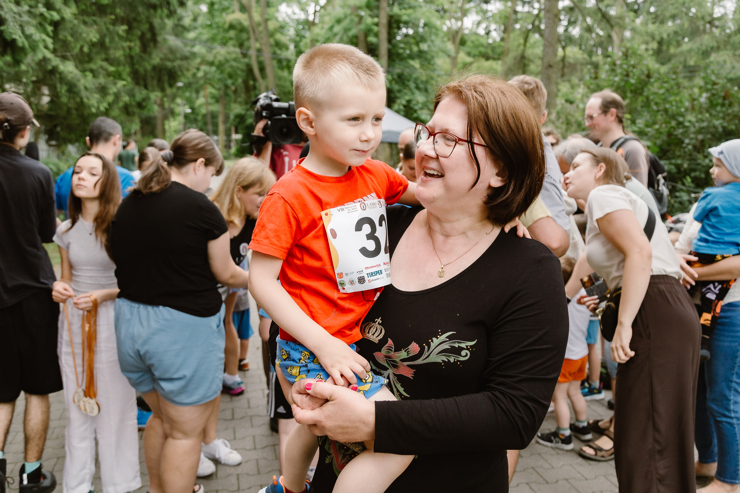 Uśmiechnięta kobieta z małym chłopcem na rękach.