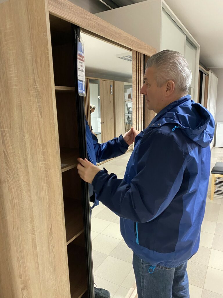 uczestnik w sklepie meblowym ogląda szafę